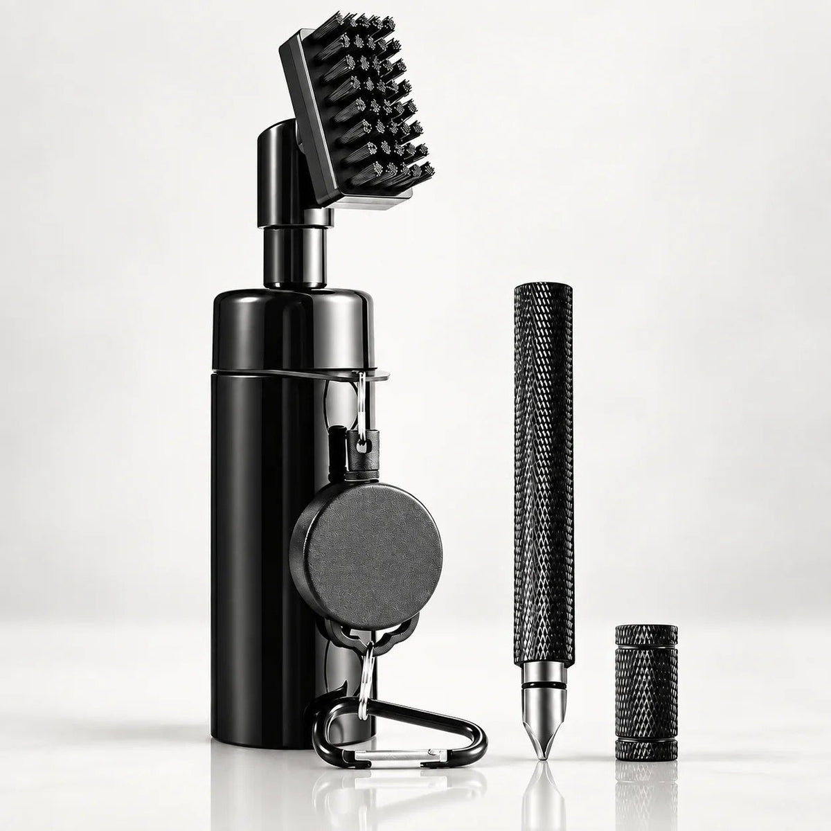 The club cleaning tool: a black brush head on a bottle-shaped handle with a retractable reel and carabiner, beside the knurled groove pick and its cap